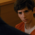 Daniel, in an orange jail jumpsuit, stares across the table at his lawyer during questioning in Cupertino.
