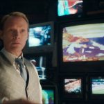 VisionQuest Ship of Theseus: Vision in a waistcoat and tie in front of a wall of old TVs in his mindscape