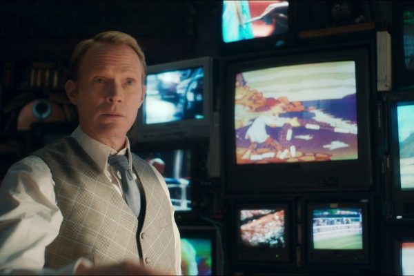 VisionQuest Ship of Theseus: Vision in a waistcoat and tie in front of a wall of old TVs in his mindscape